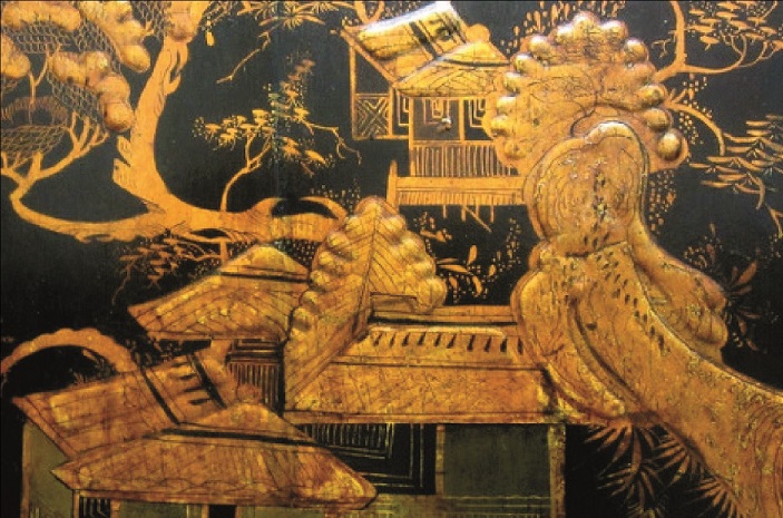A close-up of gold painted japanning on a black cabinet