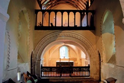 Interior of St Nicholas Church, Compton facing altar and showing small square window of former anchorhold at bottom left
