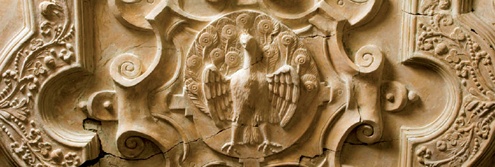 Plasterwork peacock surrounded by elaborate scrollwork