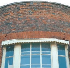 Broken flat segmental arch  with cracked bricks above left and right hand edges of window opening