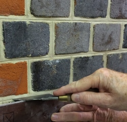 Close-up of traditional jointing tool being guided along the mortar joint