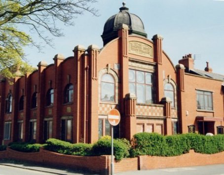 The red Accrington brick, stone and terracotta facade of Blackpool Synagogue, surmounted by a hexagonal lead-covered cupola