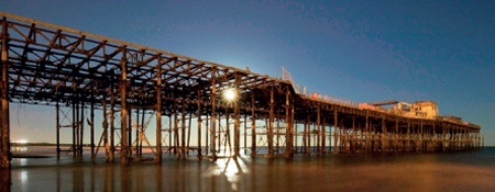 The sun shines through the skeletal remains of Hastings Pier