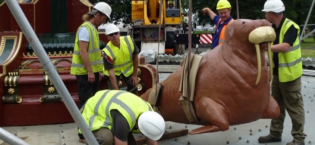 A crane lowers a restored and repainted cast-iron walrus into position
