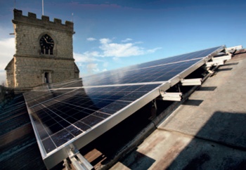PV panels fixed to a church lead roof, with church tower and clock in background