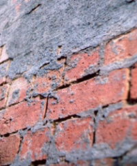 Close-up showing damaged red brick surfaces and mortar-stripped joints caused by inappropriate abrasive cleaning