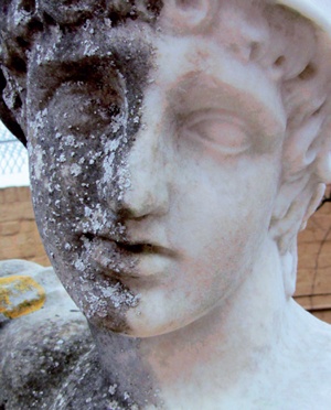 Garden statue with one half of face cleaned to show condition before and after treatment