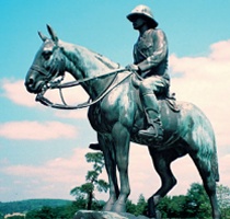A bronze equestrian statue depicting a pith-helmeted cavalry officer looking out from a scarp