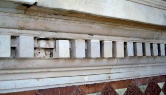 Stone dentils beneath a cornice: the replacement dentils are poorly matched and one has detached