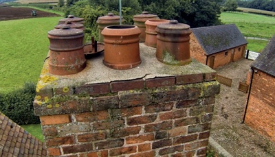 Brick chimney stack and chimney pots, some with caps, photographed from drone