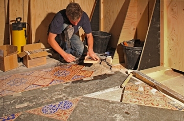 With a plywood screen behind him, a craftsman beds a new tile in mortar at the Palace of Westminster