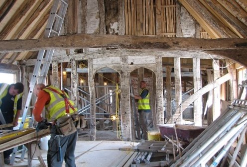 Builders at work in a timber-framed guildhall