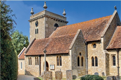 The compact exterior of St John, Stadhampton, its tower finished with stone urn finials at each corner