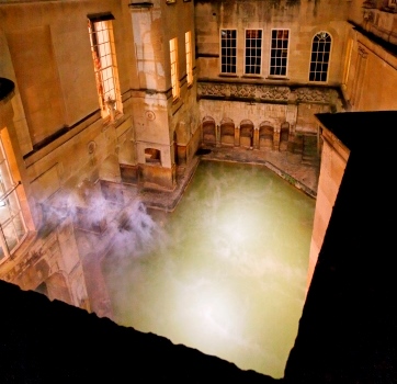 Steam rises from the illuminated King's Bath at night
