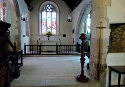 Flagged stone floor with altar and stained glass window in background
