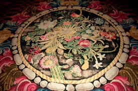 Close-up of the Blue Drawing Room carpet showing that patches of the central medallion's black ground have disappeared as the dye has deteriorated