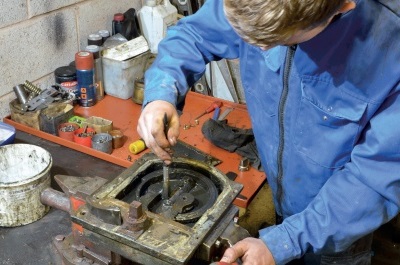 An engineer at a workshop bench works on the exposed mechanism of a floor spring