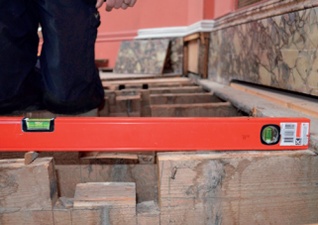 A spirit level laid along a joist shows the gallery floor sloping towards its outer edge 