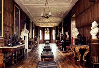 Long gallery with timber floor and wall panelling and lined with marble busts mounted on pedestals