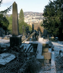 View from the cemetery with obelisk to left and city of Bath through trees in the distance