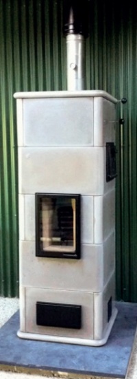 Masonry stove clad in ceramic tiles and standing on a slate plinth