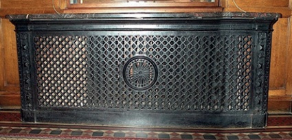 Radiator enclosure with patterned front grille including central sun motif