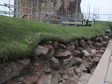 Turf soft capping follows the contours of an irregular masonry wall at a heritage site