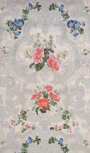 Bright red and blue flowers with sprigs of greenery adorn a reproduction wallpaper for Uppark House