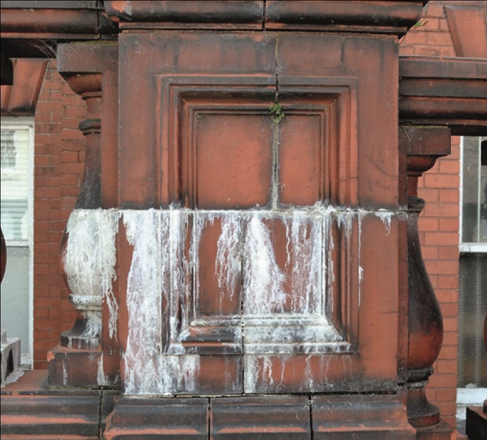 A central join across the terracotta balustrade has fee lime leaching through, leaving streaks down its lower half