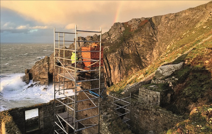 A photo of scaffolding on Lundy island, with a professional using it to reach and closely assess a chimney stack