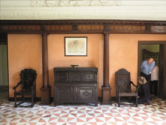 Inside Sir Francis Drake's 17th century home, showing a hallway with intricately carved wooden furniture