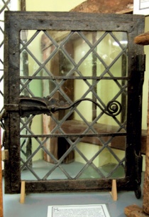 Early casement window with leaded panes and elaborate metal latch terminating in spiral form