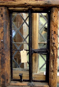 Black-painted iron window in heavily descayed timber frame