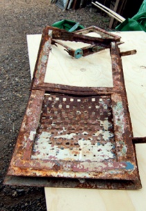 Badly rusted metal frame with pierced panel below top-hung light