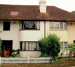 Neighbouring terraced houses, one retaining original metal windows which follow the curve of the bay, the other with modern uPVC replacement windows