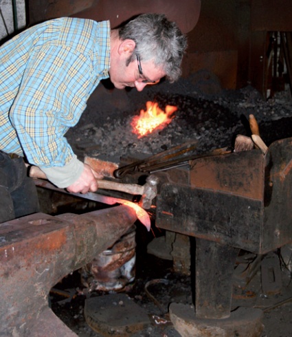 Blacksmith working at anvil with forge in background