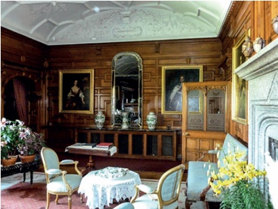 Timber-panelled drawing room with period furnishings, decorative plaster ceiling and partially glazed door