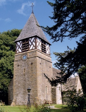 Masonry church tower topped by timber-framed belfry with louvred windows and pitched slate roof