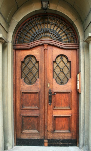 Exterior double wooden doors sheltered by stone portico