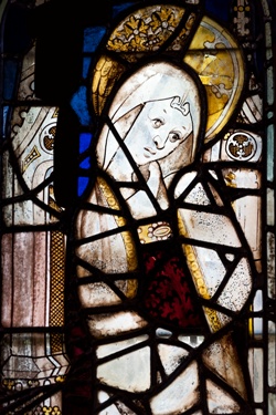 Stained glass depiction of a female figure with halo