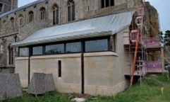Modern church extension in stone with pitched roof in terned steel