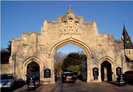 The cemetery entrance screen with the crest above the main central arch, which is flanked by two smaller arched openings for pedestrian access