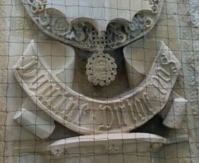 Repaired scroll with delicate stone medallion suspended from lower edge of shield above it