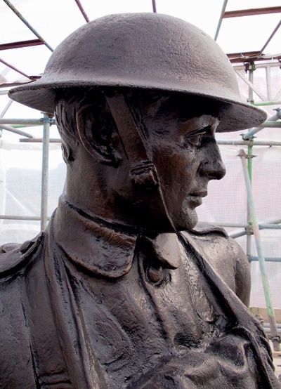 The head and shoulders of the memorial's uppermost figure with shrouded scaffolding in the background