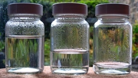Three sealed jars containing different quantities of water, all with condensation above water level
