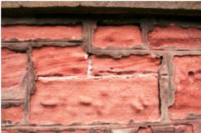 Sandstone walling repointed with a modern mortar, accelerating decay