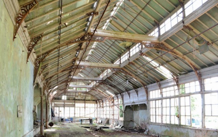 Interior of dilapidated Victorian greenhouse with rusting ironwork, broken windows and peeling paint