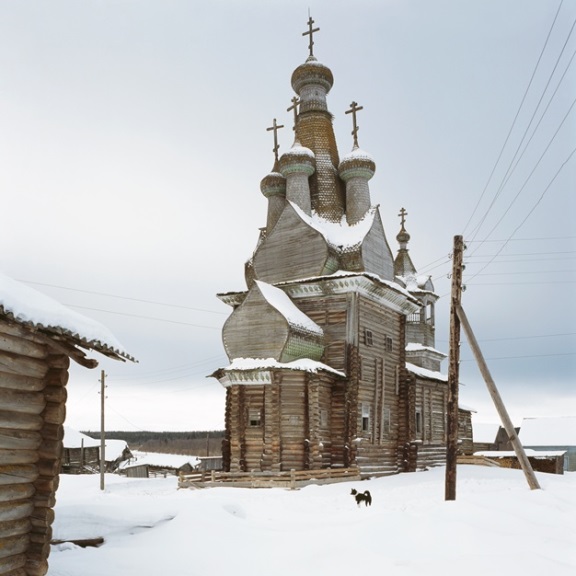 Snow-clad timber church with onion domes surmounted by orthodox crosses