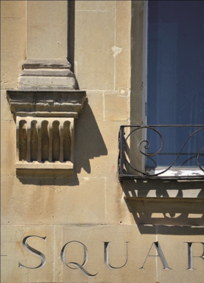 A close-up of letters carved into a limestone building in Bath