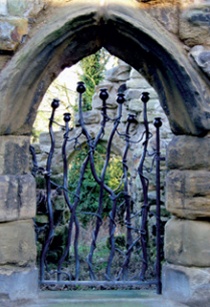 Modern decorative iron gate set in historic stone archway